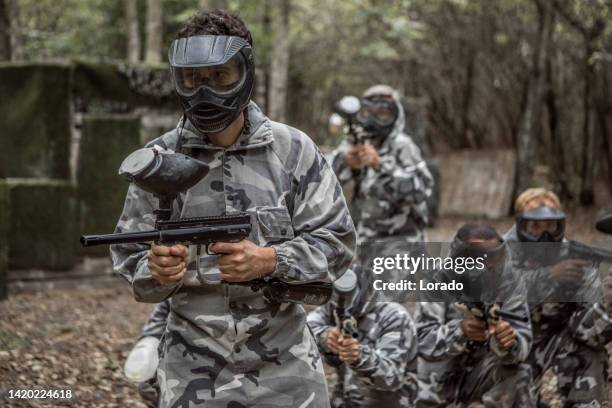 a mixed race middle aged male paintball team in action - paintball stock pictures, royalty-free photos & images