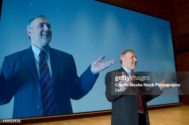 caucasian businessman making speech in front of monitor - discorso programmatico foto e immagini stock