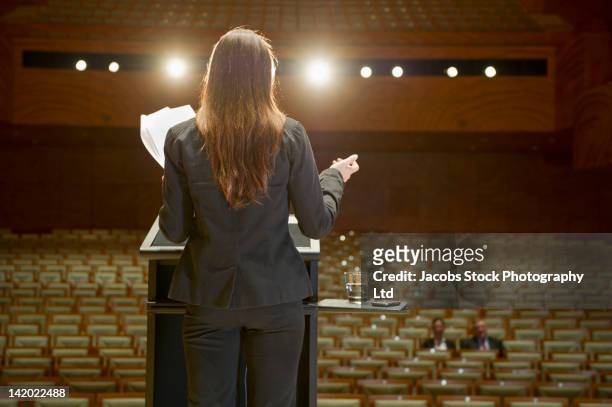 hispanic businesswoman practicing speech in empty auditorium - keynote ansprache stock-fotos und bilder