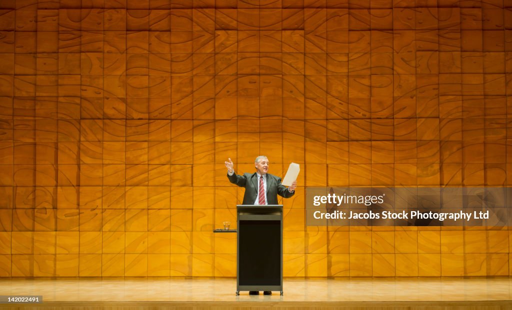 Caucasian businessman practicing speech in empty auditorium