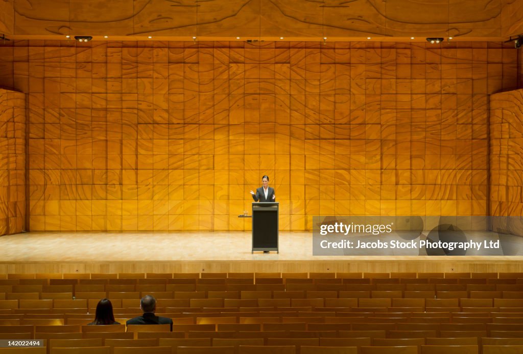 Hispanic businesswoman practicing speech in empty auditorium