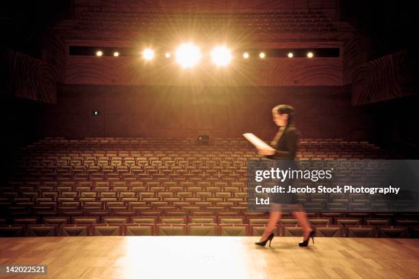hispanic businesswoman walking across stage in empty auditorium - speech rehearsal stock pictures, royalty-free photos & images