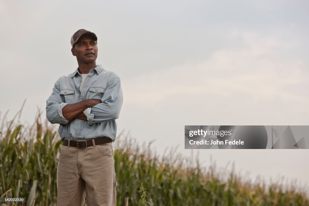 African American man standing in field with arms crossed