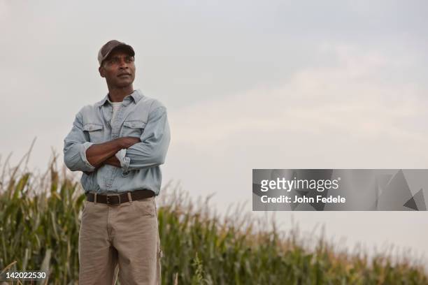 african american man standing in field with arms crossed - african american farmer stock pictures, royalty-free photos & images