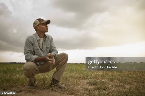 african american farmer checking dirt in field - african american farmer stockfoto's en -beelden