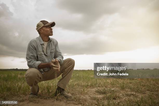 african american farmer checking dirt in field - farmer stock pictures, royalty-free photos & images