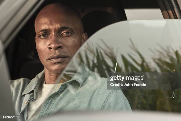 serious african american man in car - autobauer stock-fotos und bilder