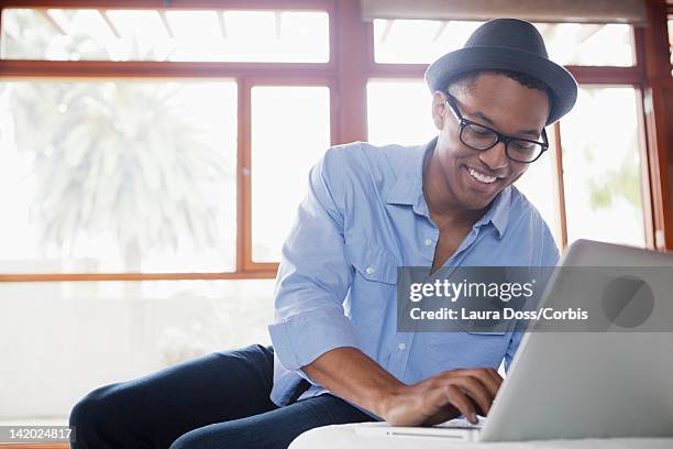 smiling man using laptop - black hat stock pictures, royalty-free photos & images