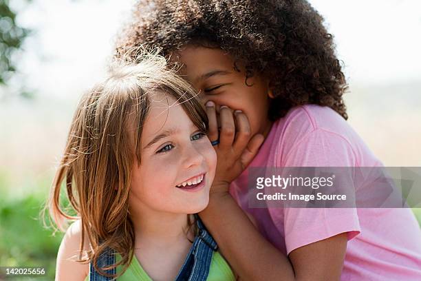 girl whispering to friend - child whispering stockfoto's en -beelden