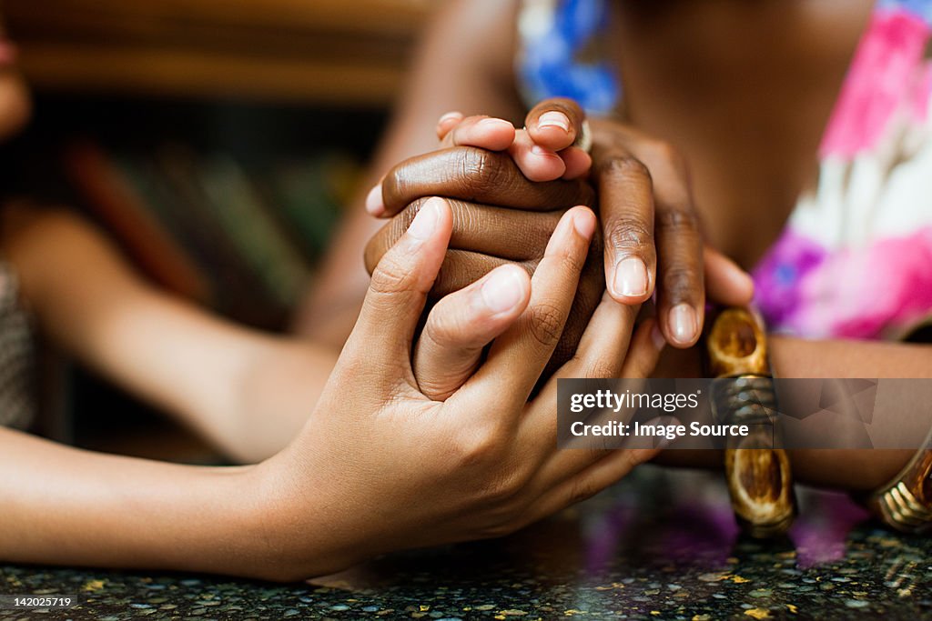 Mother and daughter holding hands in cafe
