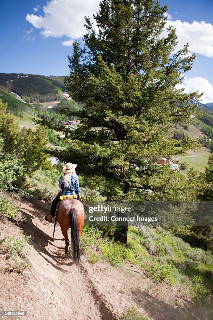 Woman horse riding through Beaver Creek, Colorado, USA