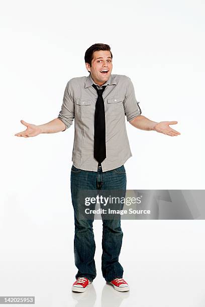 young man shrugging shoulders against white background - scrollare le spalle foto e immagini stock