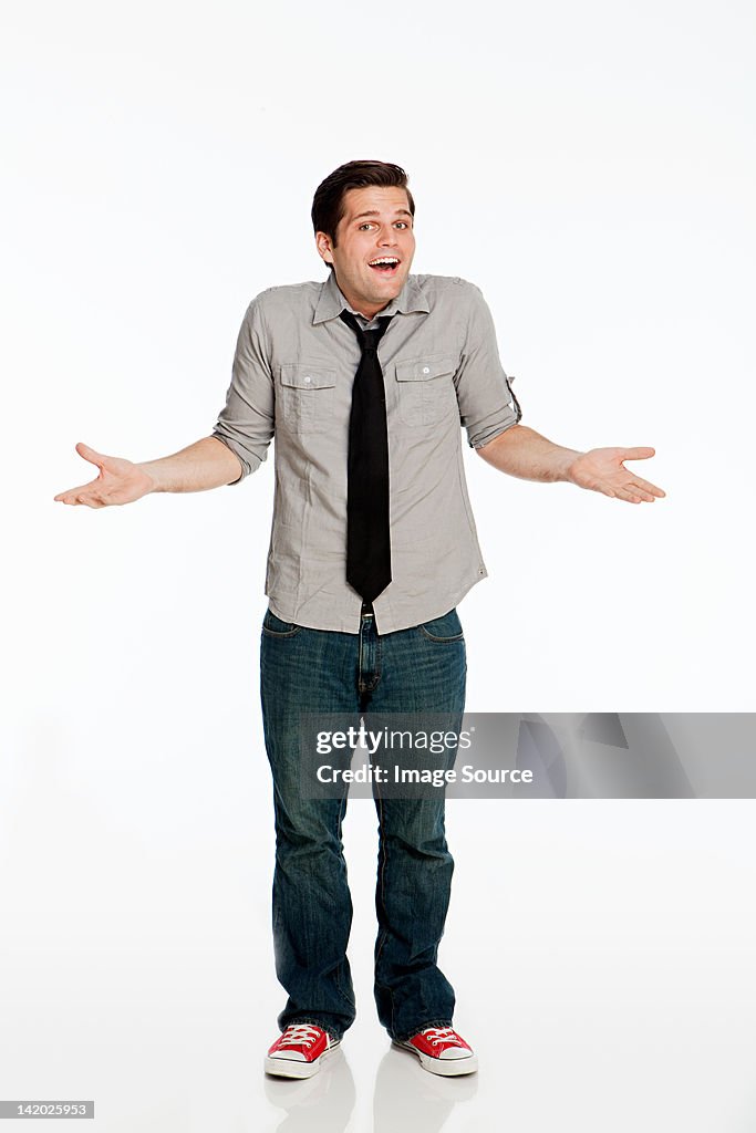 Young man shrugging shoulders against white background