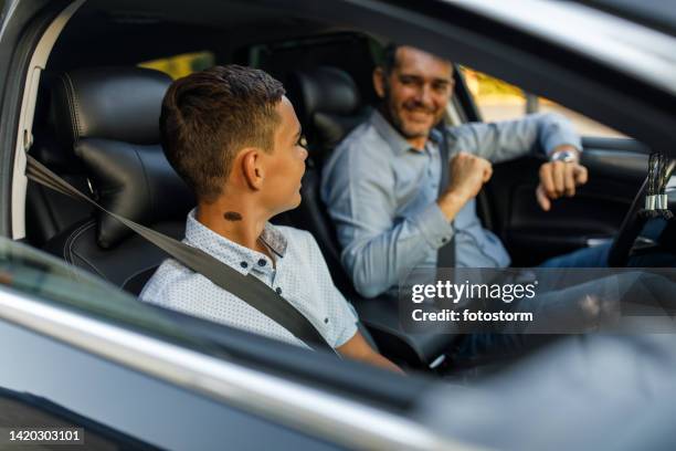 teenage boy looking at his father who is jamming to music while sitting in the car - embarrased dad stockfoto's en -beelden