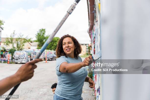 mid adult woman painting - cleaning graffiti stock pictures, royalty-free photos & images