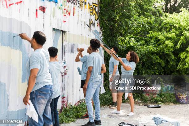 volunteers paint over the graffiti wall - cleaning graffiti stock pictures, royalty-free photos & images