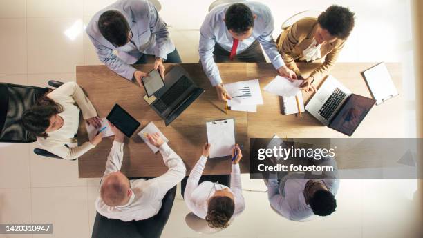 diverse group of business people sitting around conference table, having a project meeting - board room table stock pictures, royalty-free photos & images