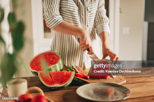 woman cutting watermelon into pieces on a wooden board - woman melons stock pictures, royalty-free photos & images