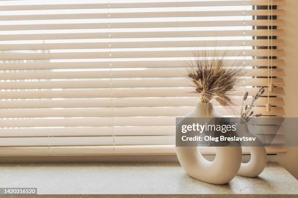 two decorative ceramic round vases with hole inside on windowsill. bouquet of dried flowers - windowsill copy space stock pictures, royalty-free photos & images
