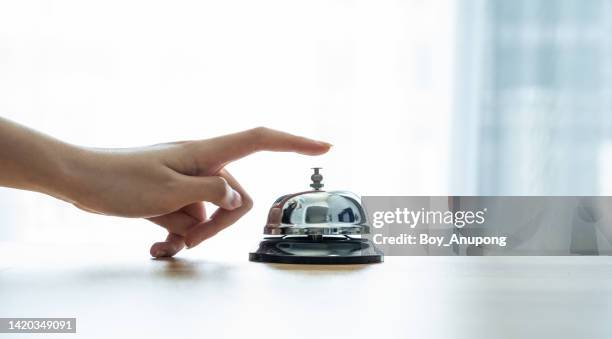 close-up of someone hand trying to call hotel reception by ringing front desk bell. - reception stock-fotos und bilder