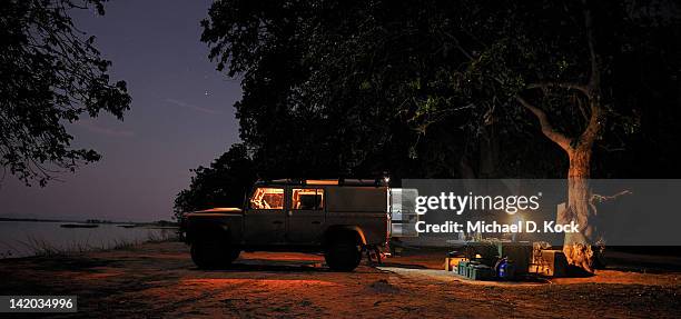 off-road car and evening campsite alongside the zambezi river, mana pools, zambezi valley, zimbabwe - car camping luggage stock pictures, royalty-free photos & images