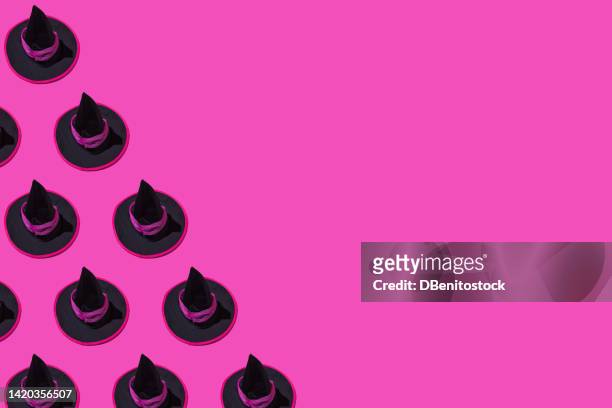 pattern of black halloween witch hats with fuchsia ornament, on the left side, on pink background. halloween, celebration, witchcraft, spell, fear, horror, autumn and october concept - witch's hat stock pictures, royalty-free photos & images