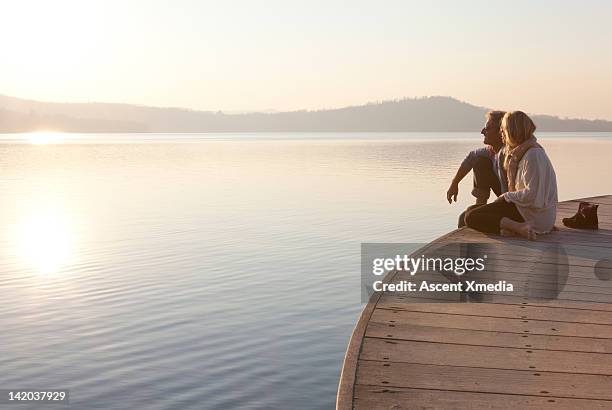 couple enjoy sunrise from wharf above lake - woman pier stock pictures, royalty-free photos & images