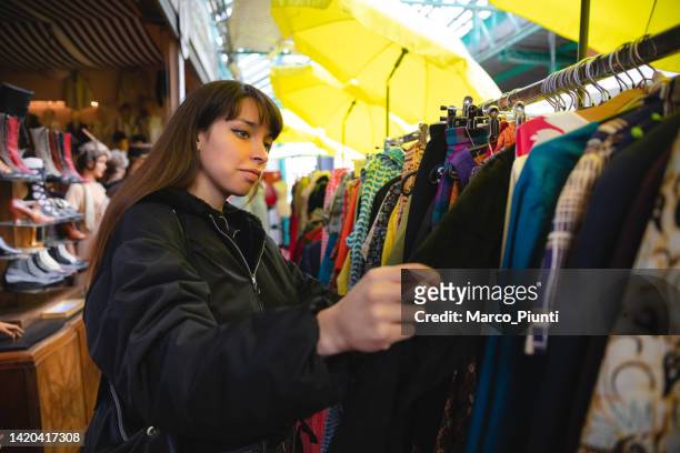 young woman shopping vintage clothing - elektromarkt stockfoto's en -beelden