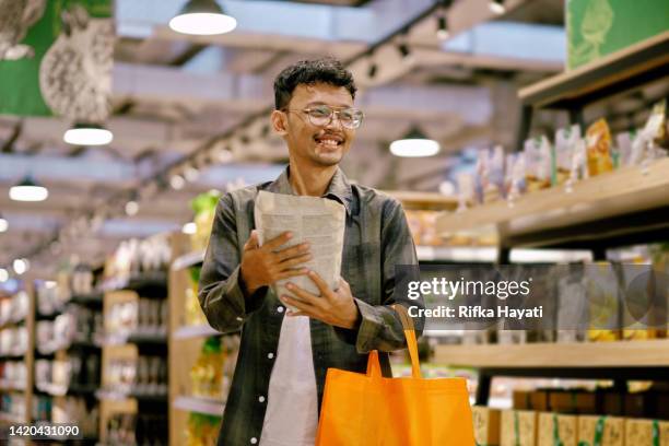 glückliches gesicht des asiatischen mannes beim einkaufen auf dem biomarkt. - supermarket bread stock-fotos und bilder