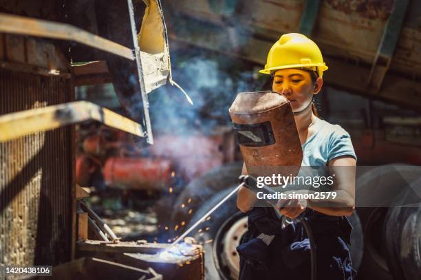 female welder with protective equipment welding metal in workshop. - ship fumes stock pictures, royalty-free photos & images