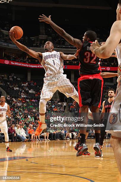 Kemba Walker of the Charlotte Bobcats shoots a layup against Ed Davis of the Toronto Raptors at the Time Warner Cable Arena on March 17, 2012 in...