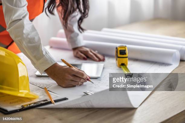 female civil engineer notes changes on blueprints by a pencil. - civil engineering fotografías e imágenes de stock