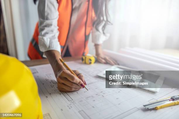 changes in construction plans noted by a female civil engineer or architect. - civil engineering fotografías e imágenes de stock