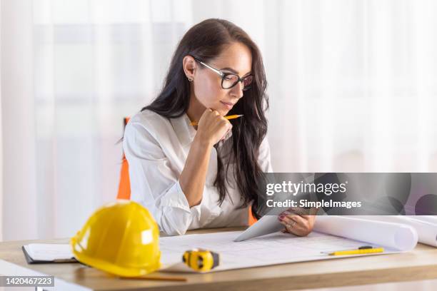 businesswoman in civil engineering reads from the tablet in the office. - workers compensation - fotografias e filmes do acervo