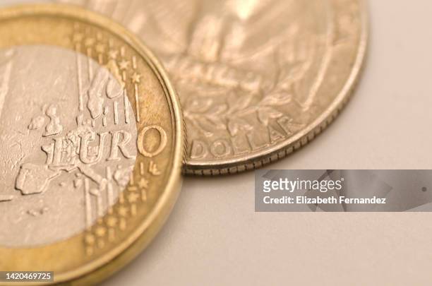 high angle view of a one euro coin and a quarter dollar coin. money concept. - one euro coin stock pictures, royalty-free photos & images