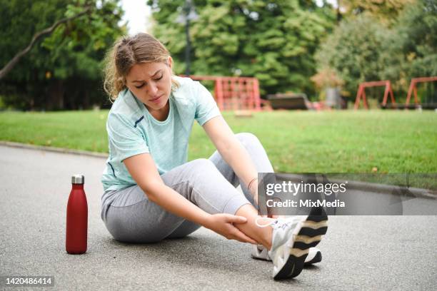 mujer se lastimó el tobillo mientras corría al aire libre - tobillo fotografías e imágenes de stock