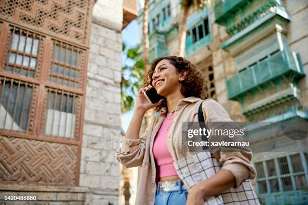 young woman walking through al-balad using smart phone - jiddah stock pictures, royalty-free photos & images