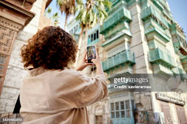 young tourist in jeddah photographing historic houses - jiddah stock pictures, royalty-free photos & images