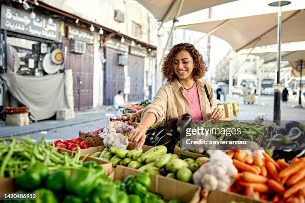 young woman grocery shopping at outdoor market - arab shopping stockfoto's en -beelden