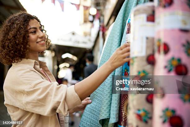 mujer sonriente de oriente medio comprando tela - zoco fotografías e imágenes de stock