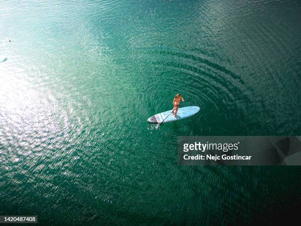 vista aérea de uma mulher se exercitando em uma prancha de stand up paddle - rep - fotografias e filmes do acervo
