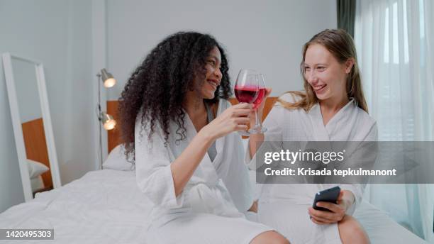 young lesbian couple telling funny stories and laughing while staying at luxury hotel. - staying in hotel stock pictures, royalty-free photos & images