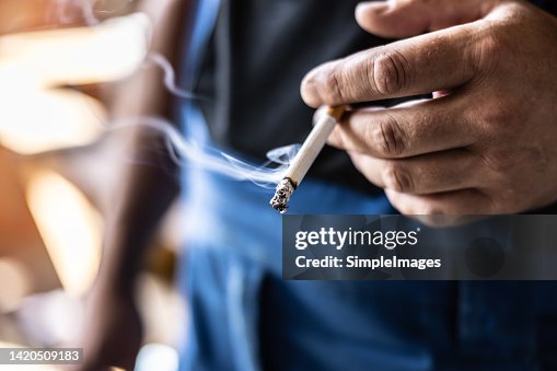 Detail of a man holding a smoking cigarette in his hand. Detail of a man holding a smoking cigarette in his hand.