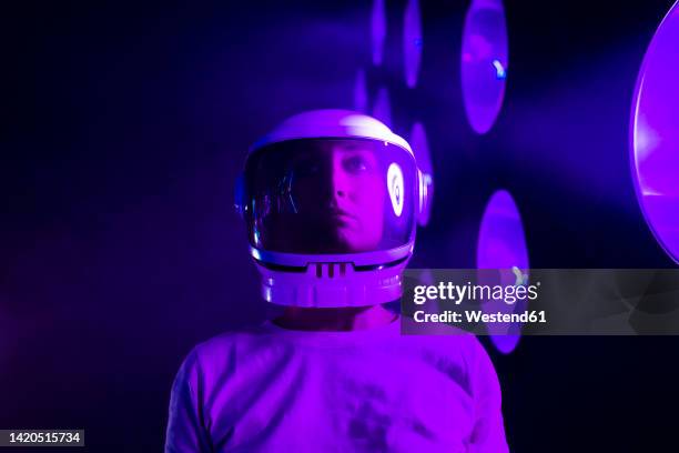 astronaut wearing space helmet by illuminated lighting - raumfahrzeug stock-fotos und bilder