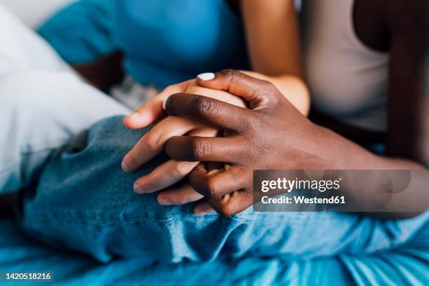 lesbian couple holding hands at home - black and white holding hands stock-fotos und bilder