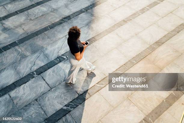 businesswoman with smart phone walking on footpath - career path stock pictures, royalty-free photos & images