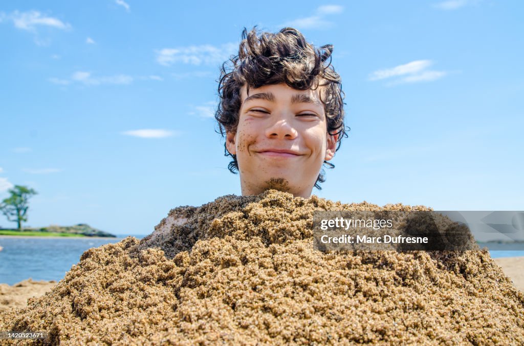 Kopfschuss eines im Strandsand begrabenen Teenagers
