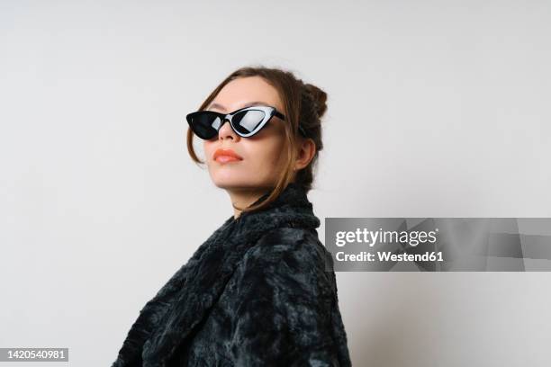 confident woman wearing sunglasses in studio - pelzmantel stock-fotos und bilder