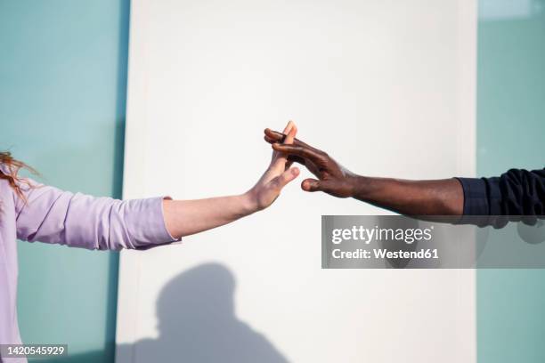 man and woman with intertwined fingers in front of wall - entrelacement photos et images de collection