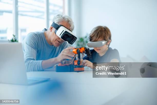 grandfather and grandson with vr glasses watching robot model at home - like ai stock pictures, royalty-free photos & images